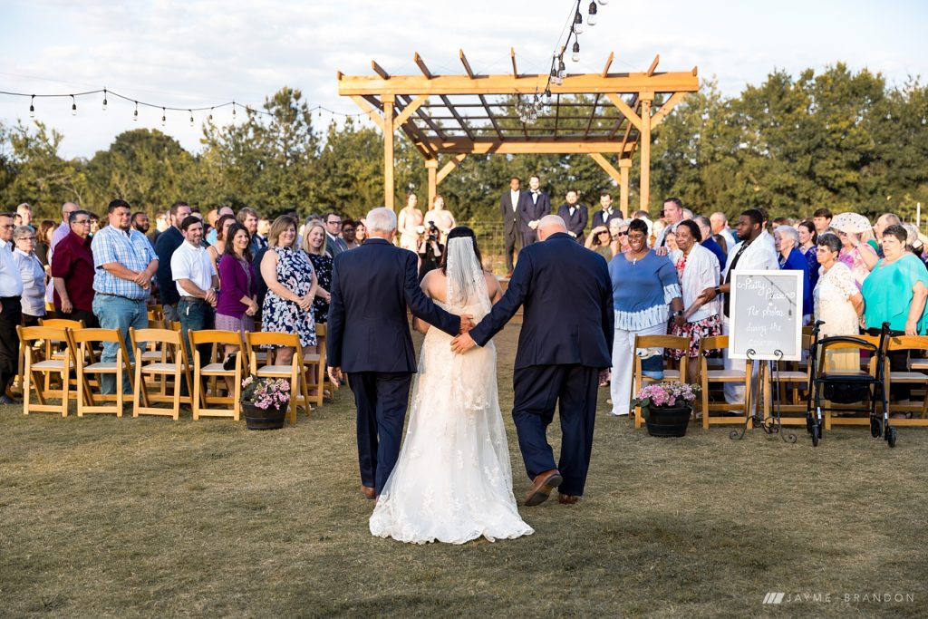 Bride walks down the aisle escorted by Uncle and Grandfather at Warehouse 535